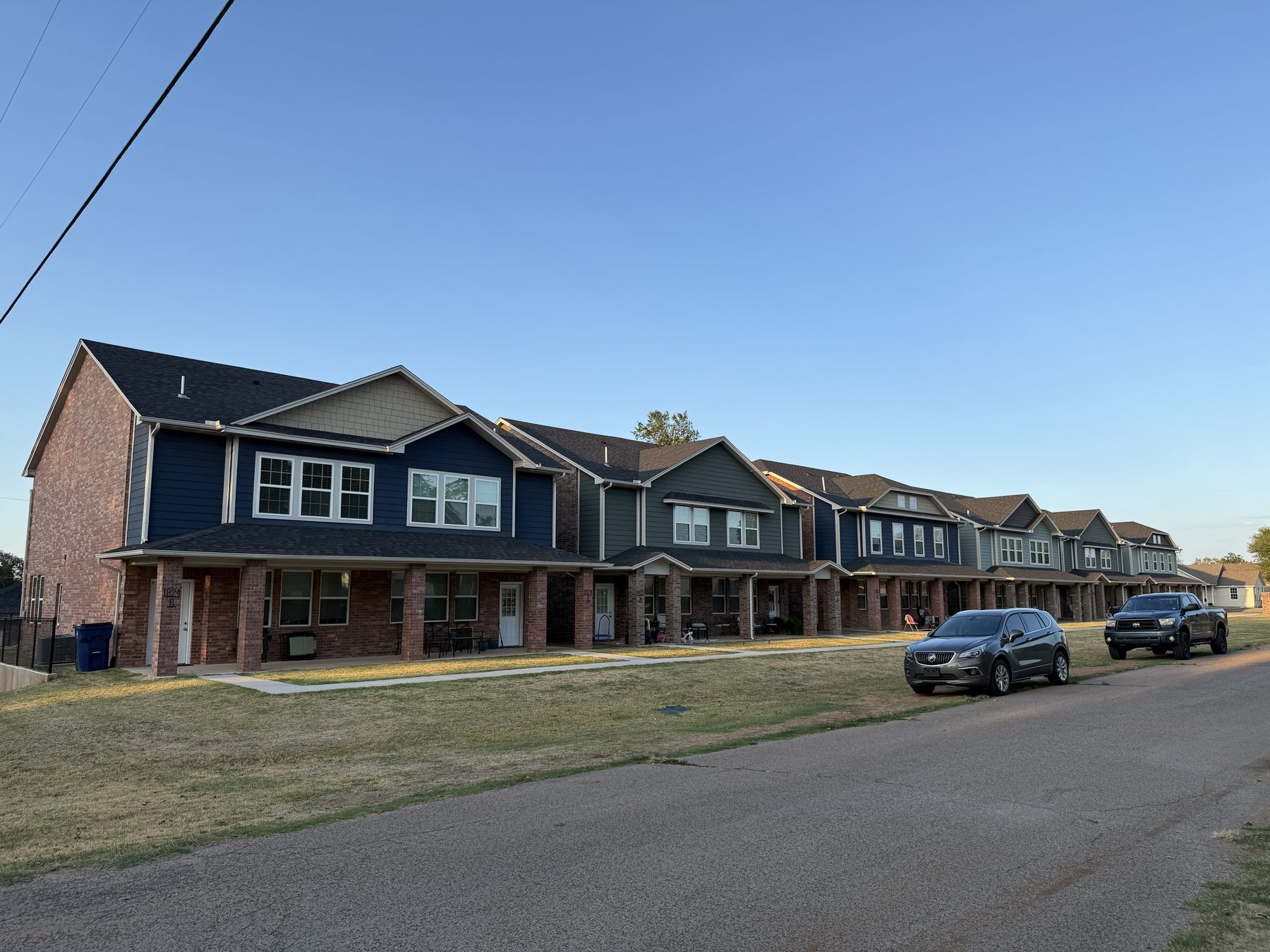 Guthrie Townhomes: the row of six paired buildings along Logan Avenue, brick porches and tapered columns, at sunset